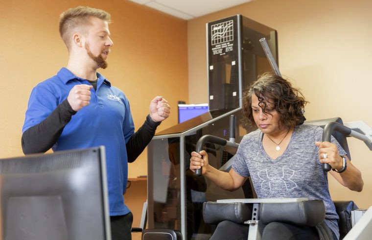 iSpine patient being trained by physical therapist to use medx equipment