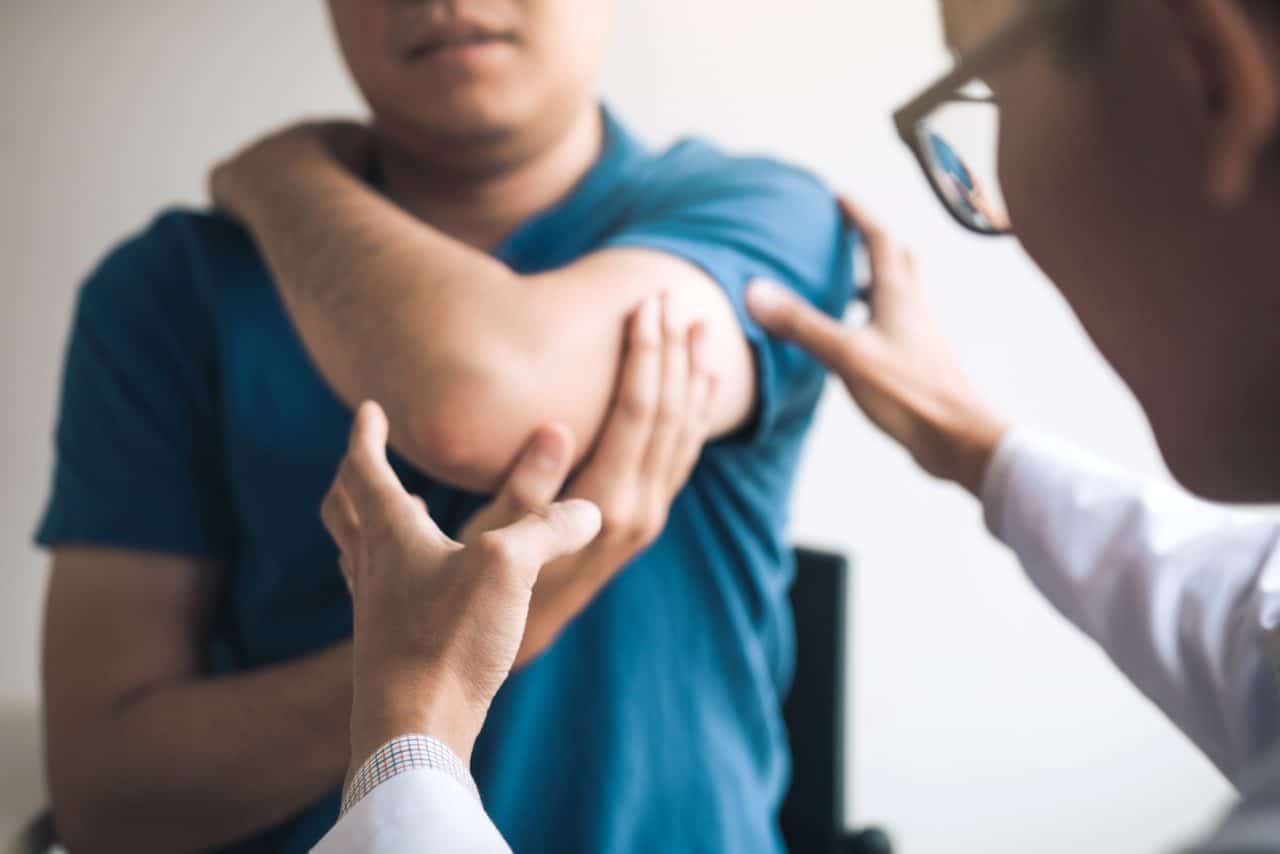 doctor patient clinic visit assessing elbow joint
