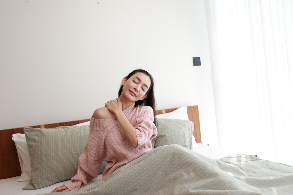 women stretching her neck while in bed